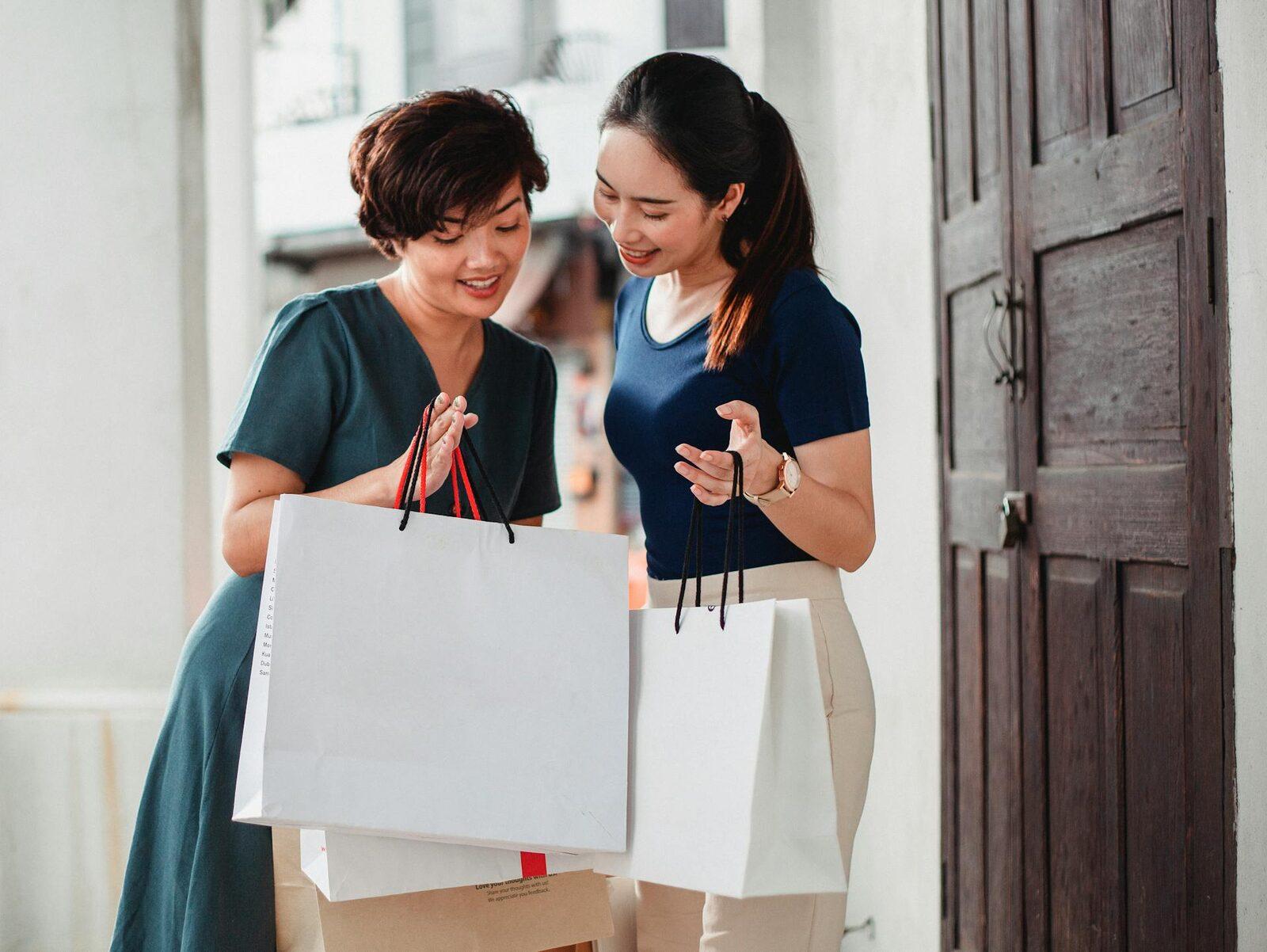 Two friends looking into their shopping bags