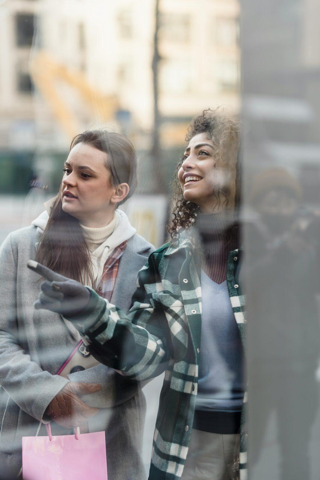 Two shoppers walking down a city street with their bags